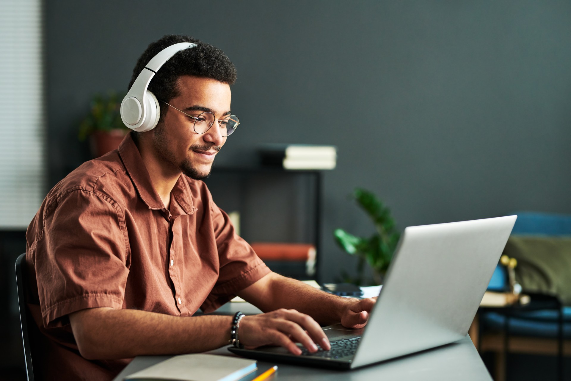 Young smiling man in headphones typing on laptop keyboard