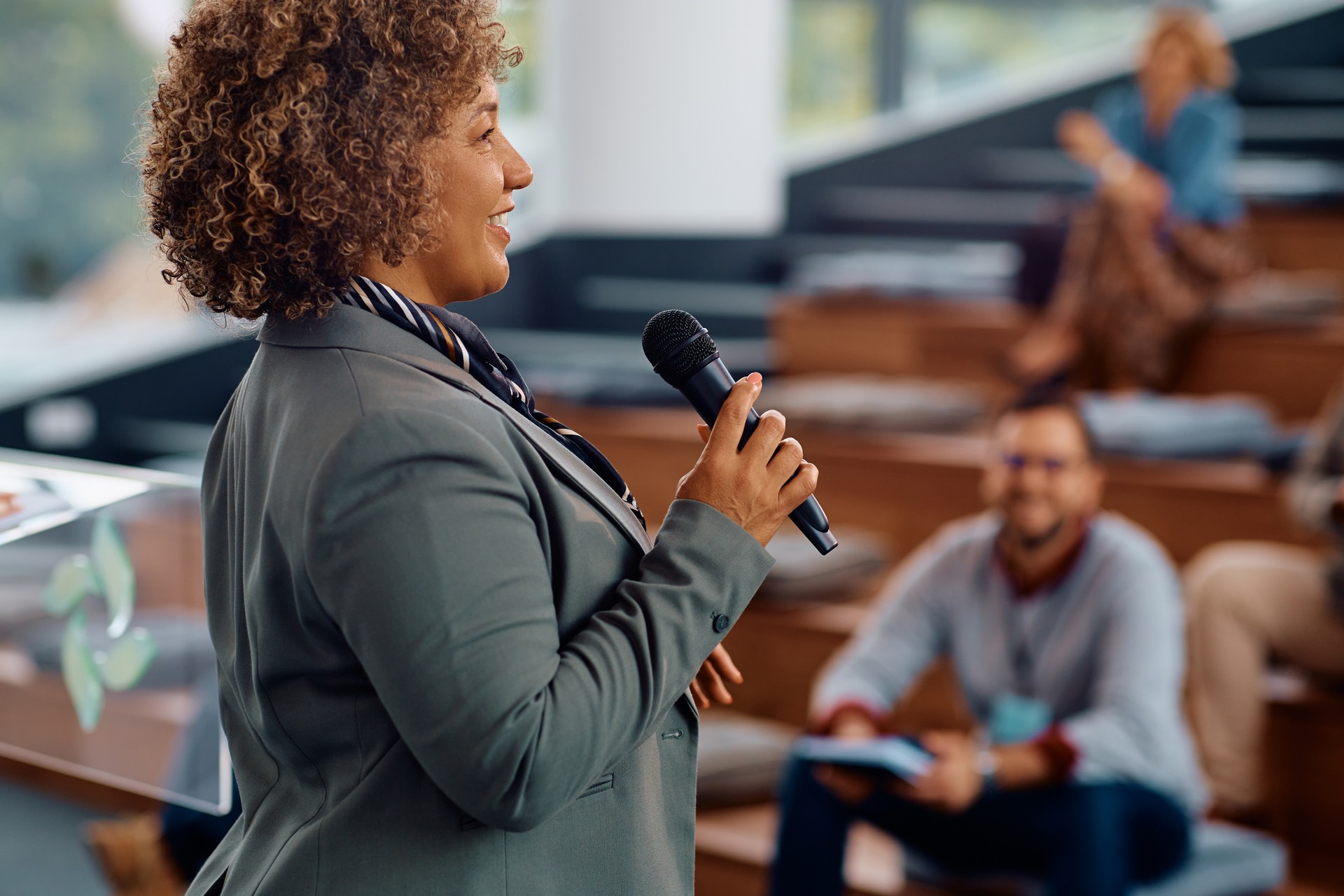 Happy female speaker talking on a business conference at convention center.